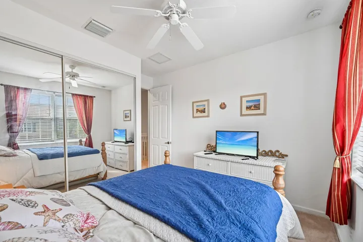 Ceiling fan, mirrored closet doors, window with blinds, white paneled door, and neutral wall color