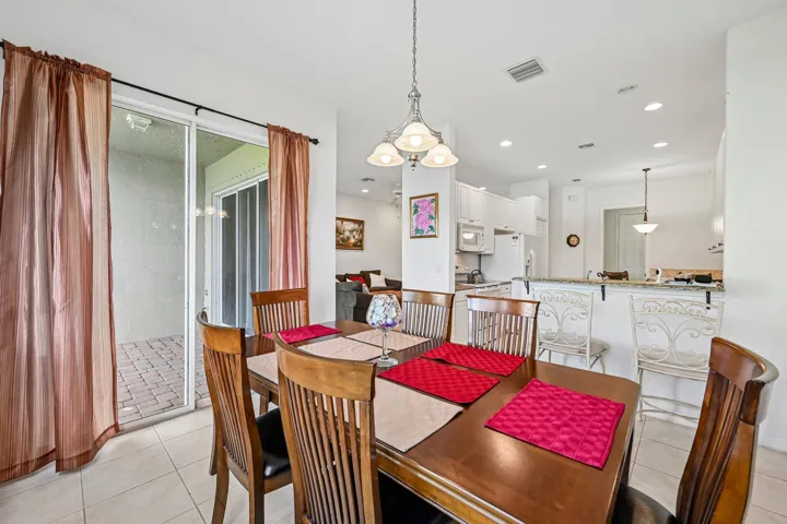 Tile flooring, sliding glass door, kitchen pass-through window, recessed lighting, and a patio with paver flooring