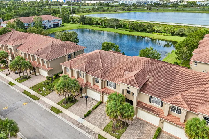 Townhome exterior with a terra cotta tile roof, beige stucco siding, and white garage doors