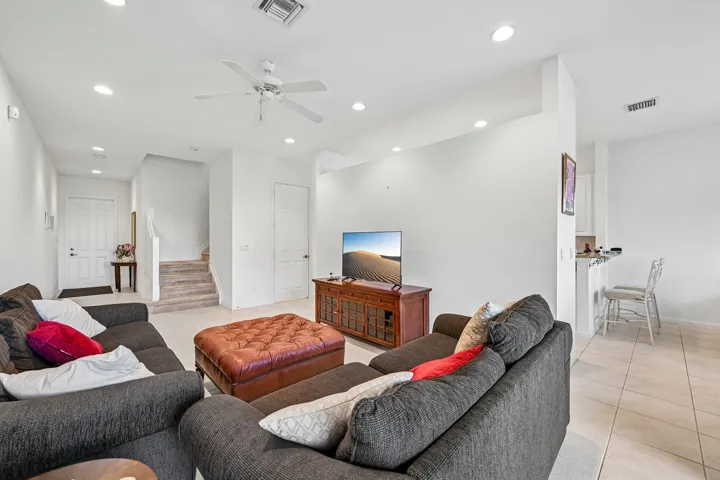 Recessed ceiling lighting, ceiling fan, staircase with carpeted treads, tile flooring, and white interior doors