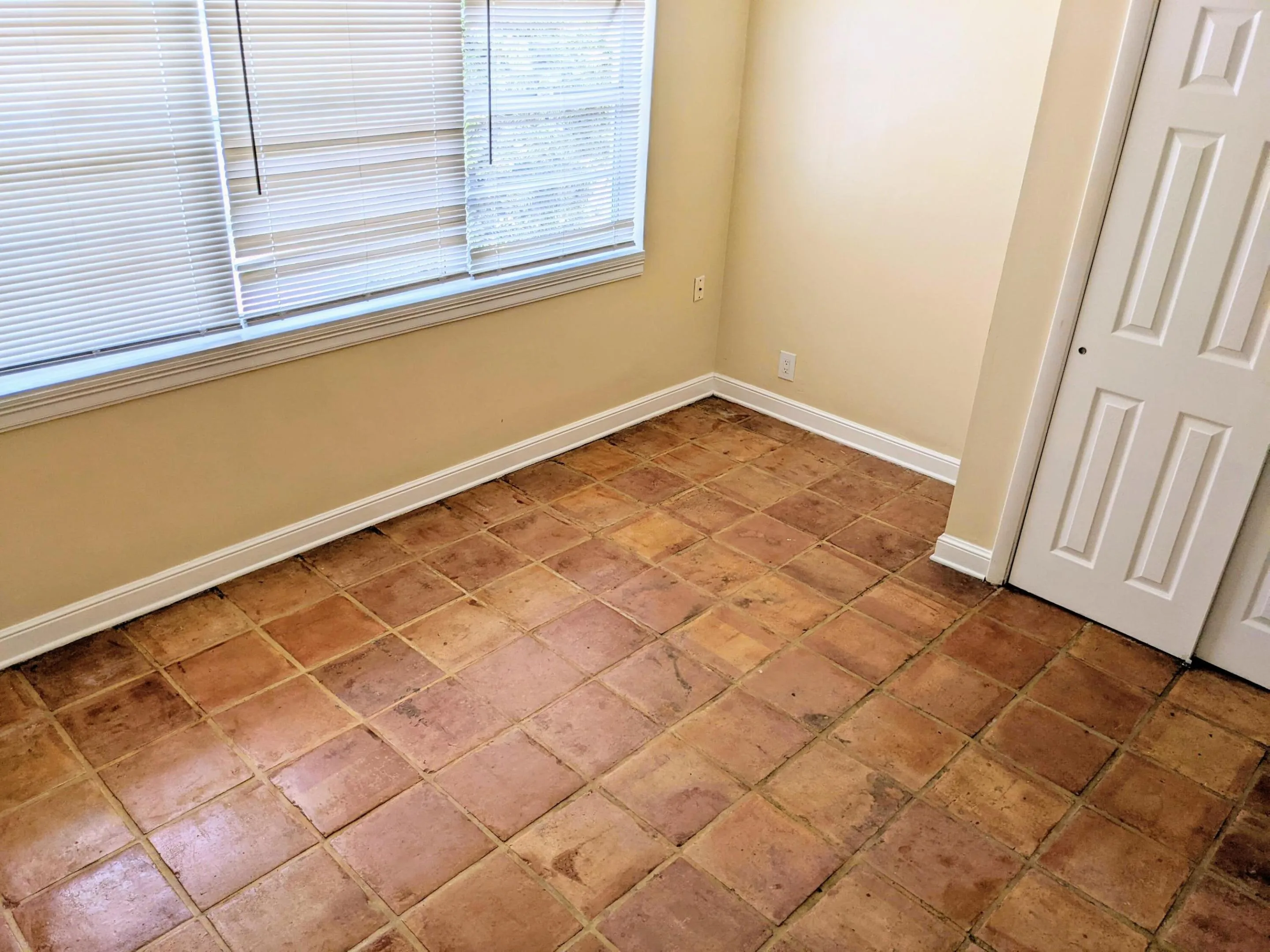 Terra cotta tile flooring, white bi-fold closet doors, and neutral wall paint