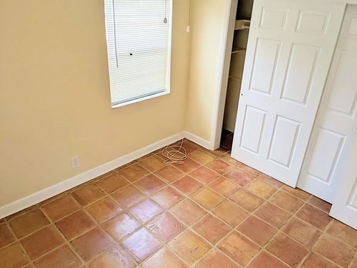 Tile flooring with a matte finish, white baseboards, and a window with horizontal blinds