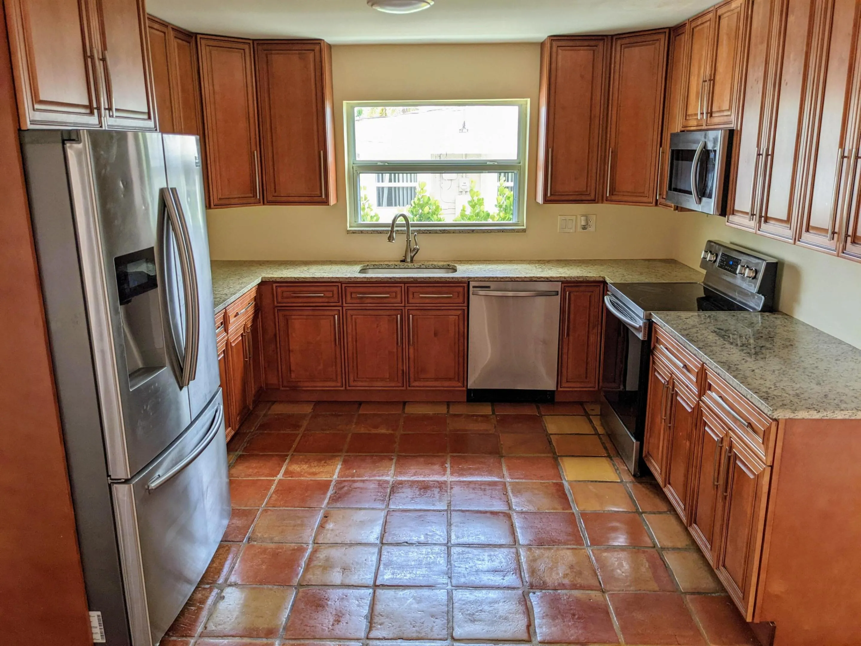 U-shaped kitchen with wood-finish cabinetry, light-toned countertops, and tile flooring