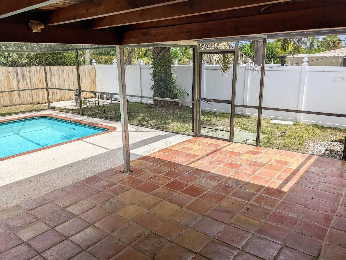 Screened lanai with terracotta tile flooring and a built-in swimming pool