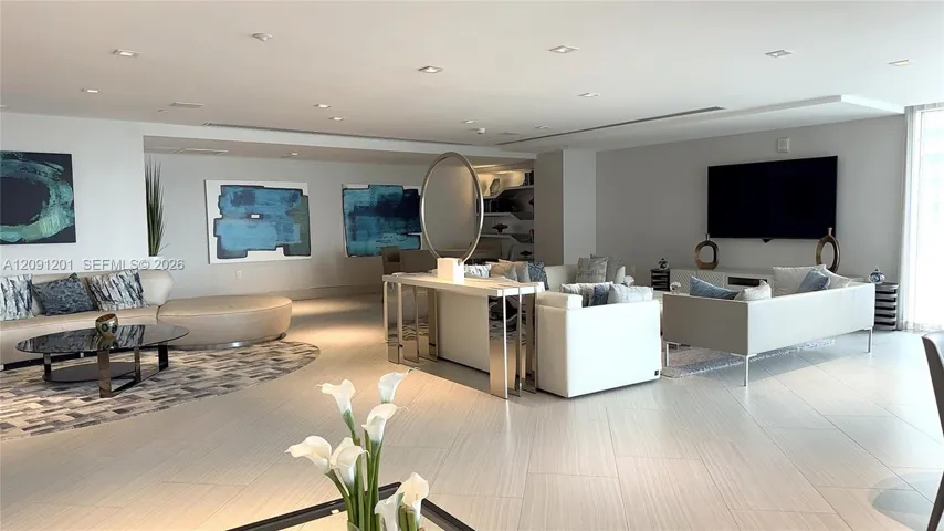 Open-concept living space featuring neutral oversized tile flooring, recessed ceiling lighting, and a wall-mounted television console