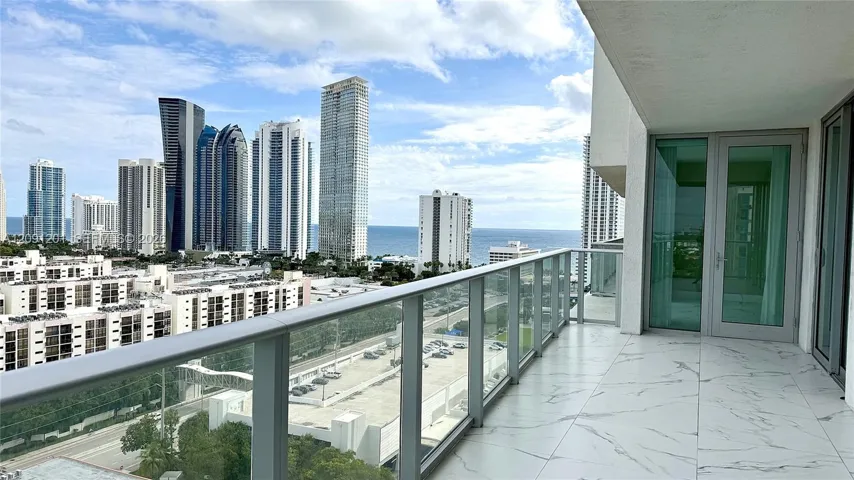 Private balcony featuring large-format light-toned stone tile flooring and glass panel railing