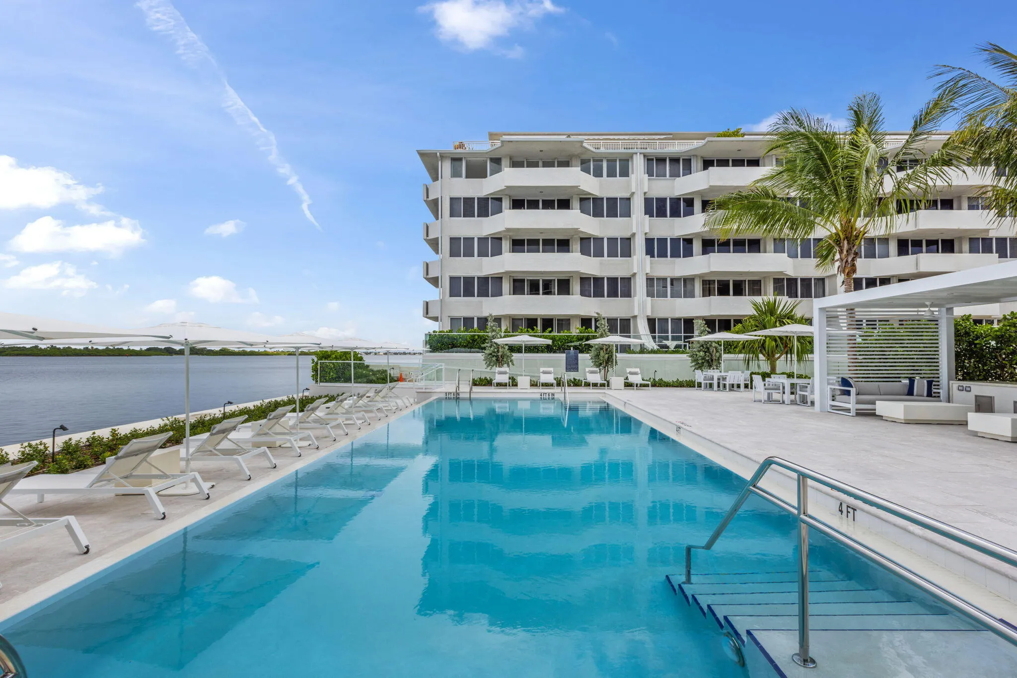 Resort-style pool area featuring a rectangular swimming pool, integrated entry steps, and a surrounding paver deck