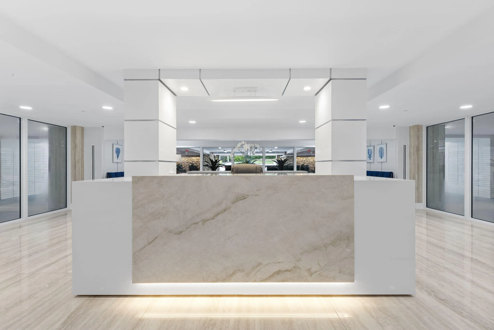 Lobby area featuring a stone-finish reception desk with integrated lighting, polished tile flooring, and recessed ceiling lighting