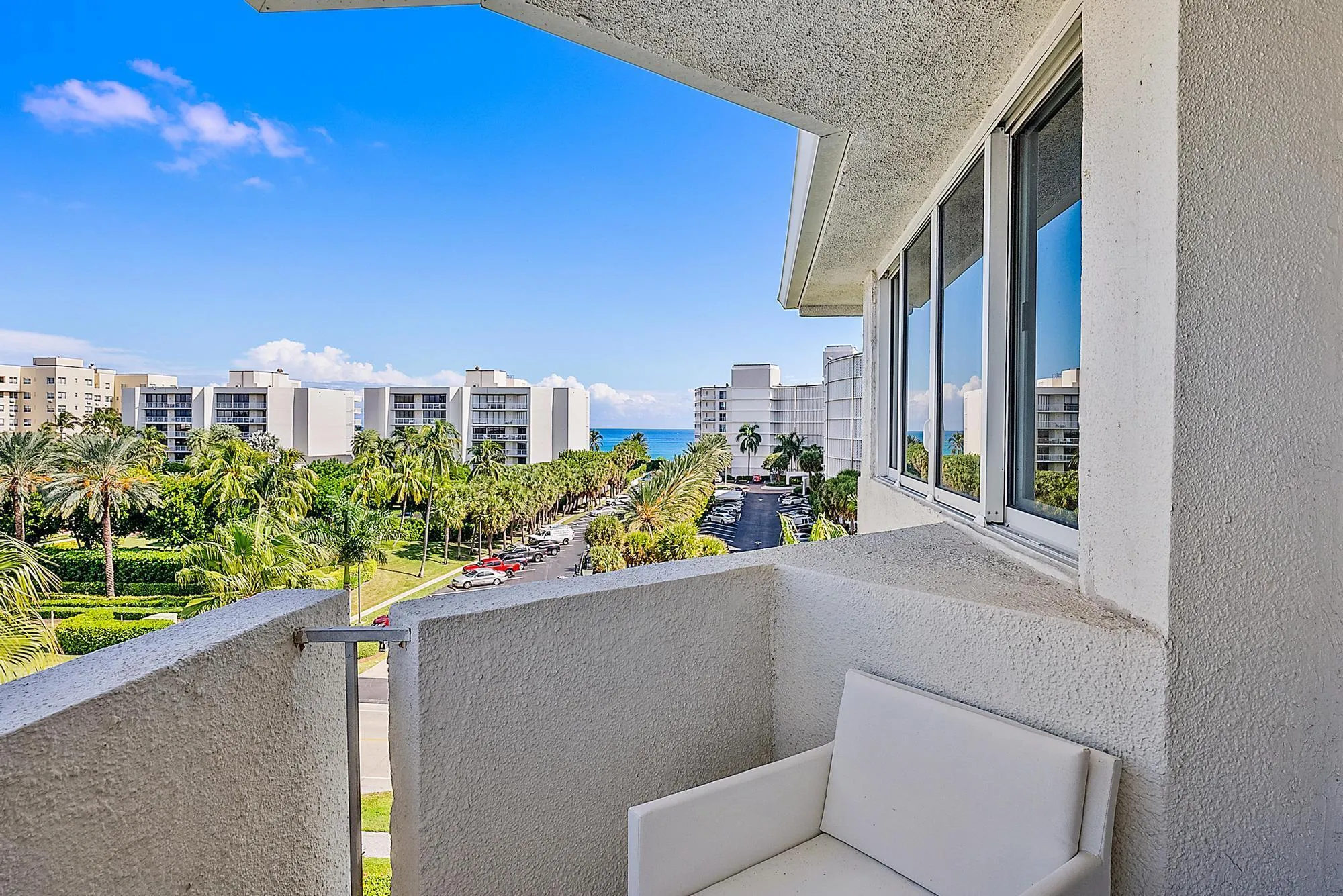 Private balcony with textured exterior walls, white-framed windows, and ocean scenery