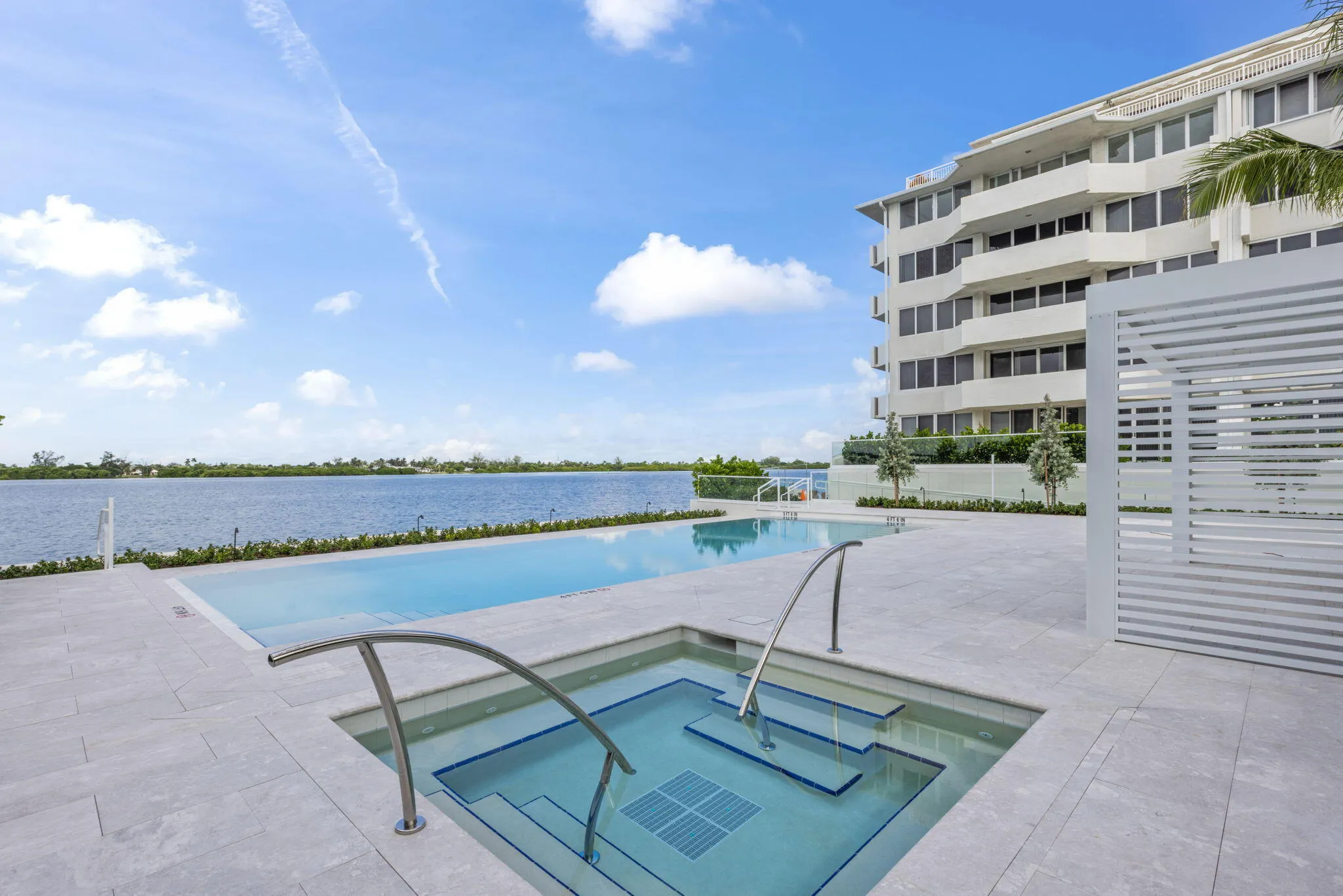 Waterfront property featuring a rectangular pool, integrated spa, and expansive patio with light-toned pavers