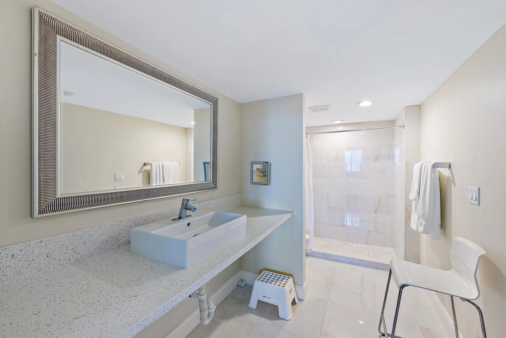 Spacious vanity with a rectangular vessel sink, expansive countertop, and large framed mirror