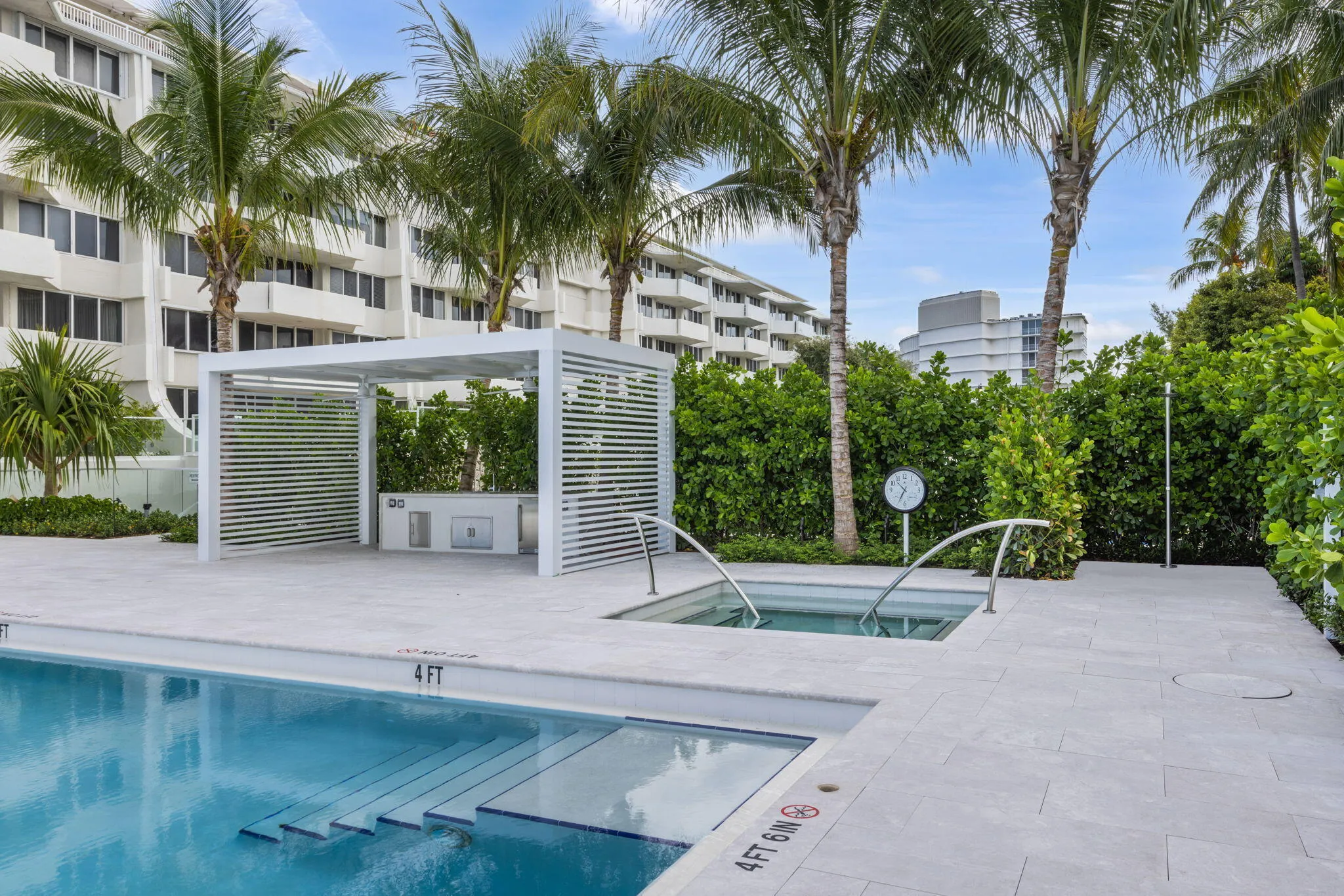 Swimming pool with integrated steps, adjacent spa, and surrounding light-toned paved deck