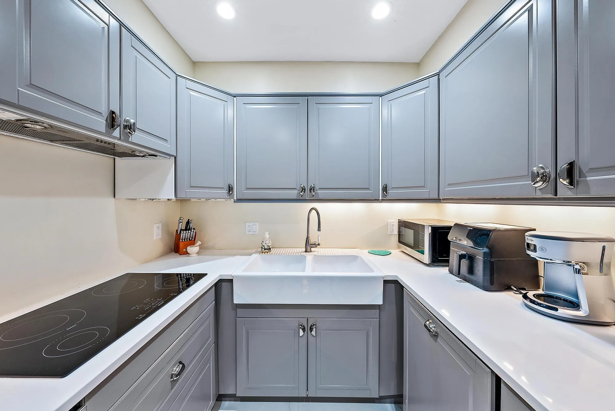 U-shaped kitchen featuring grey shaker cabinetry, white countertops, a flat-top electric range, and an apron-front sink with a gooseneck faucet