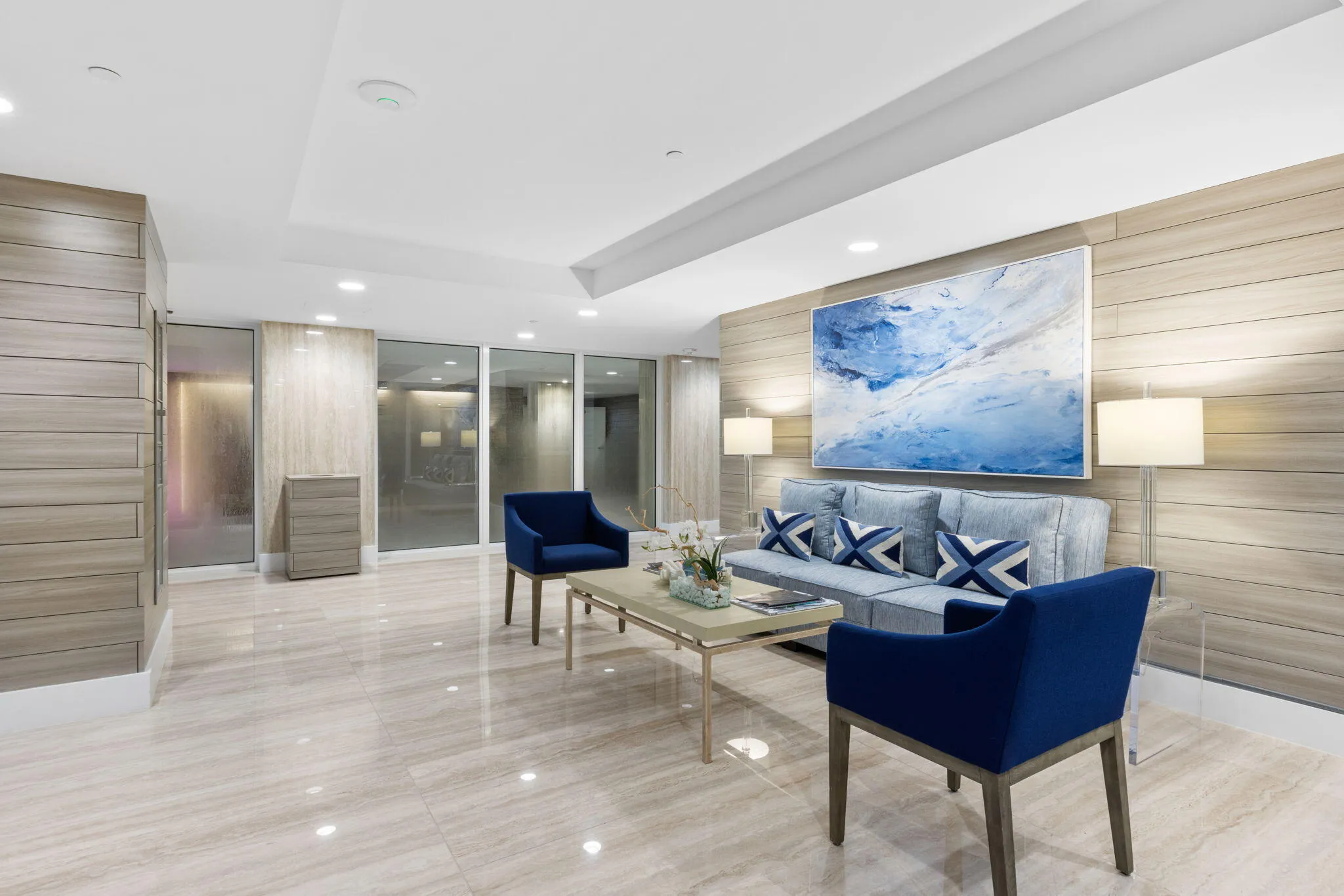 Polished stone flooring, recessed lighting, floor-to-ceiling windows, and wood-finish accent walls define this space
