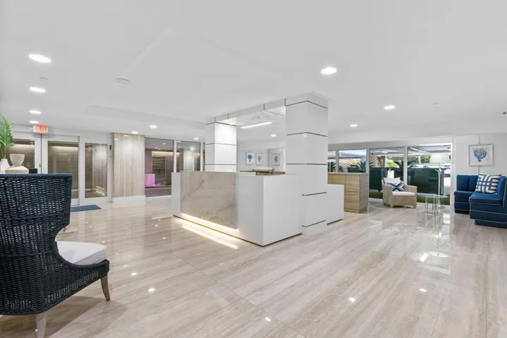 Lobby featuring polished stone-finish flooring, a reception desk with stone detailing, recessed lighting, and expansive window panels