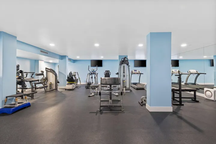 Fitness center featuring multiple exercise machines, mirrored wall, recessed lighting, and rubber flooring