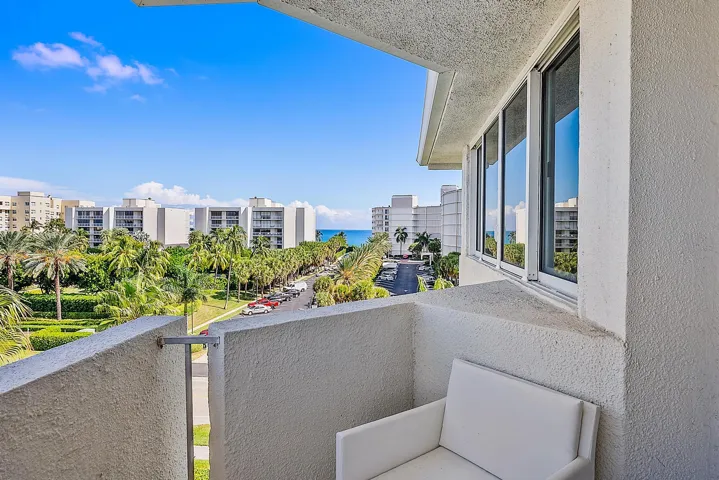 Private balcony with textured exterior walls, white-framed windows, and ocean scenery