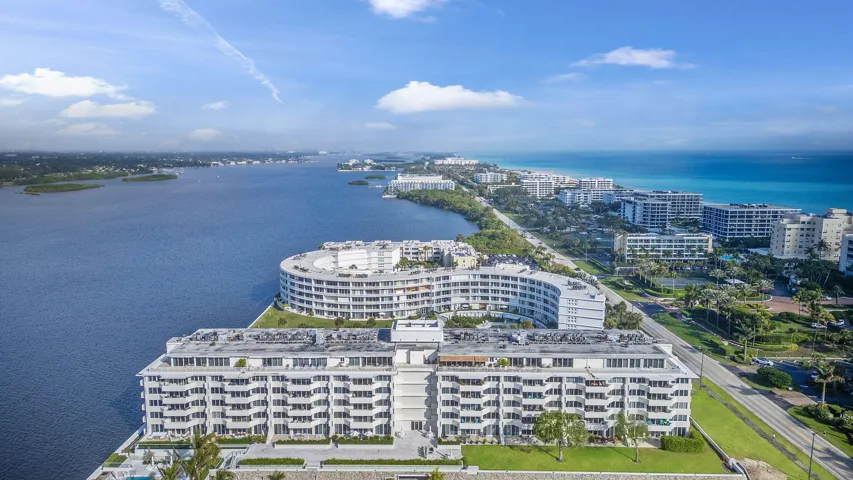 Waterfront residential building with multiple balconies, positioned along a waterway with a prominent ocean backdrop