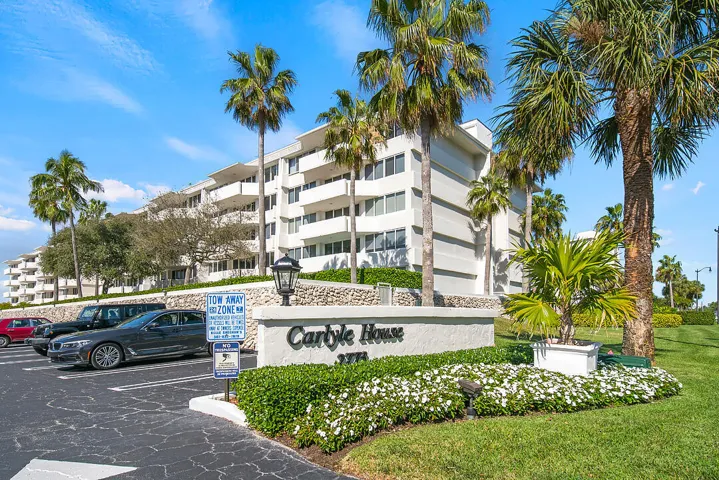 Building exterior with multiple balconies, surrounded by mature palm trees