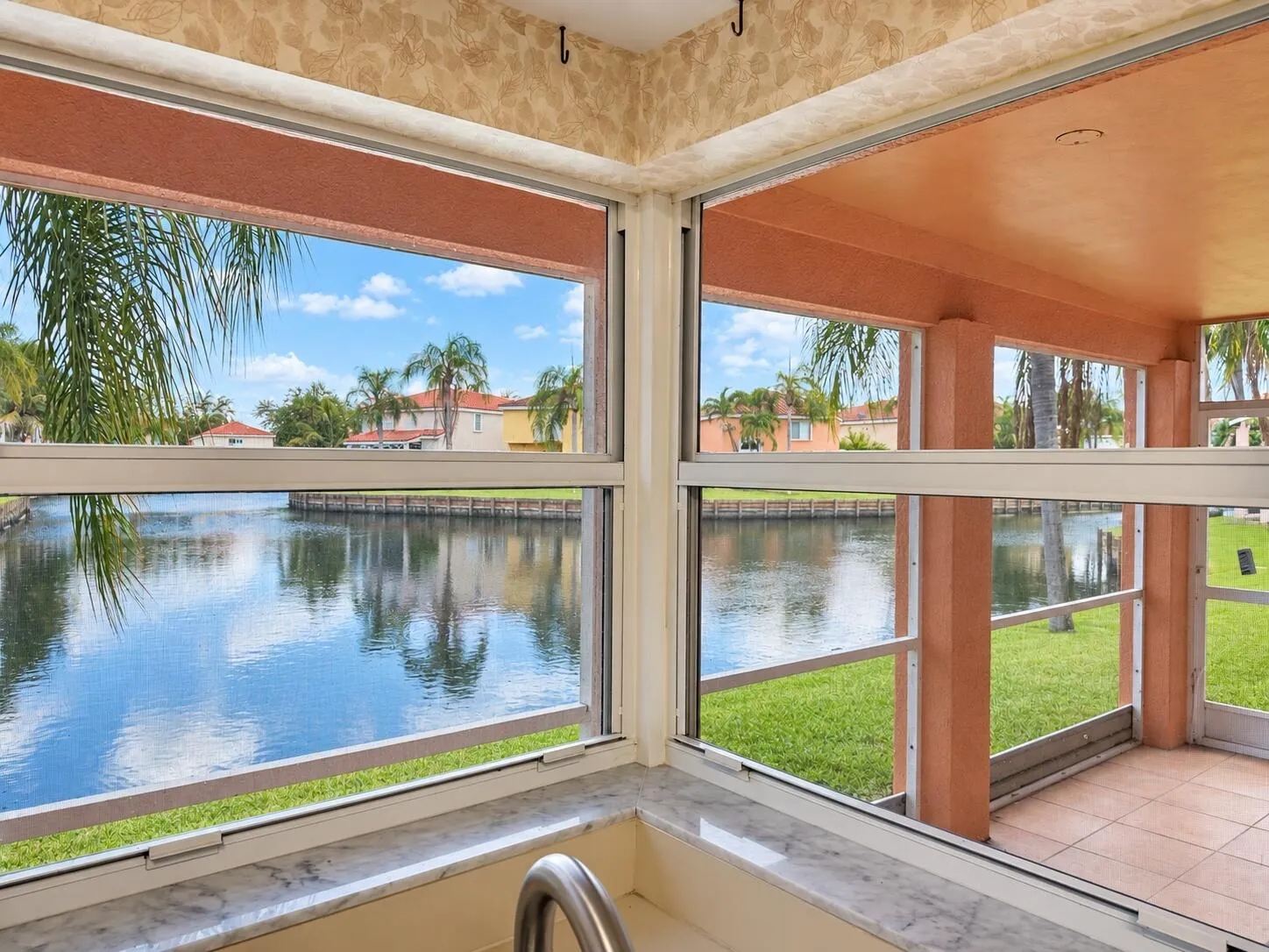 Waterfront setting with expansive windows, a screened patio, and a marble-finish windowsill