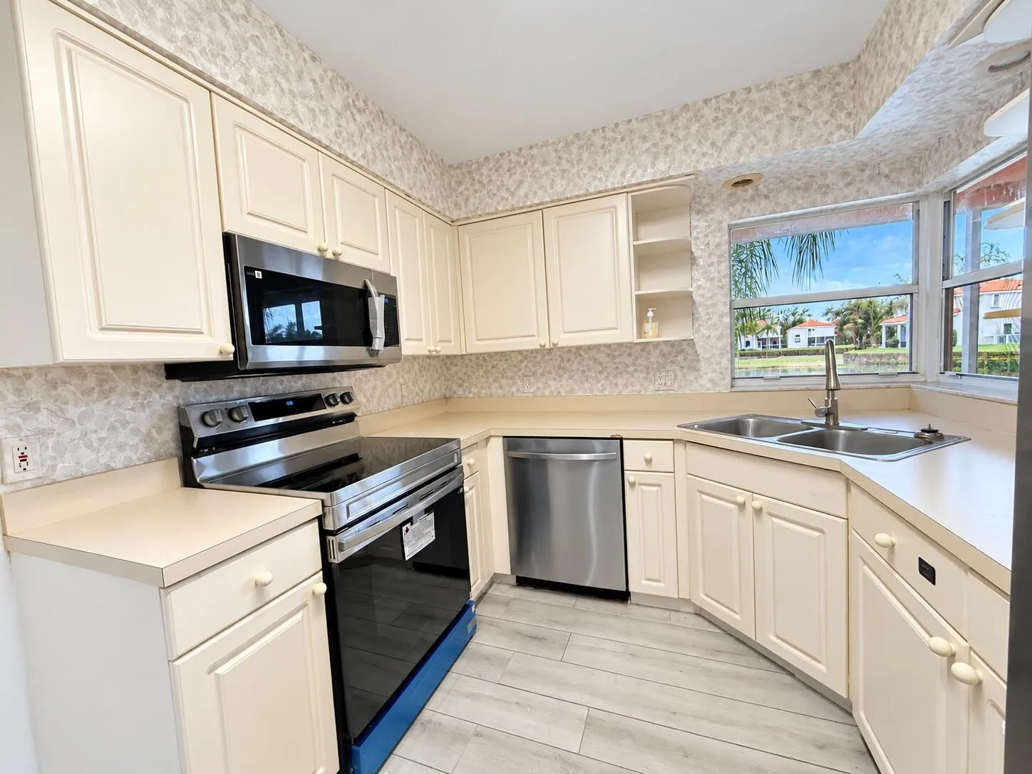 Kitchen featuring stainless steel appliances, dual basin sink, light-toned cabinetry, light-toned countertops