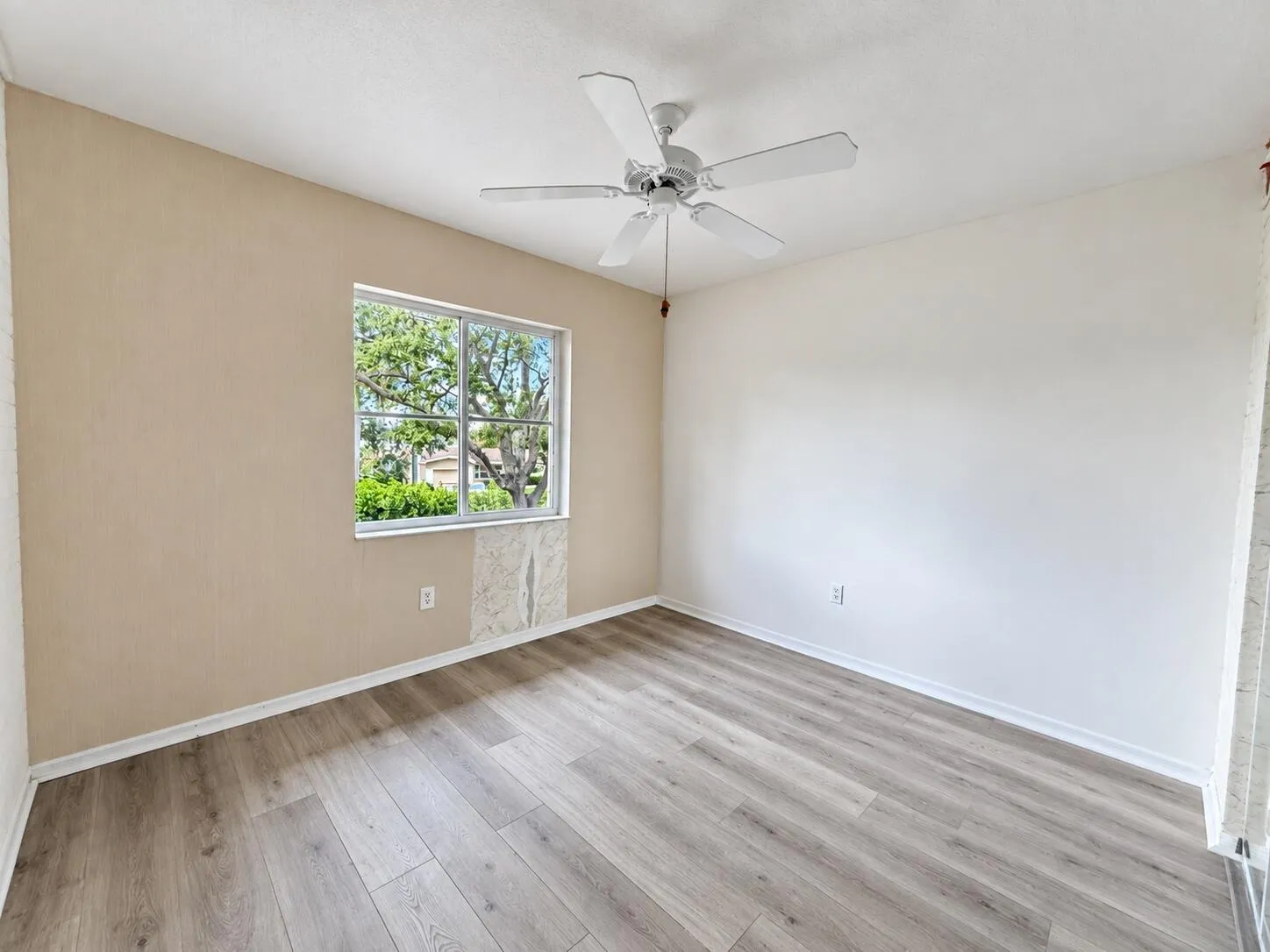Wood-finish flooring with a white trim, complemented by a ceiling fan