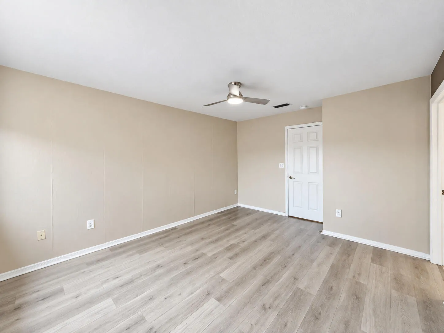 Light-toned wood-finish flooring, neutral wall paint, white trim, and a ceiling fan with integrated lighting