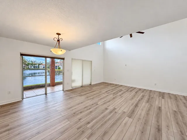 Vaulted ceilings with a ceiling fan, wood-finish flooring, and sliding glass doors leading to a private patio