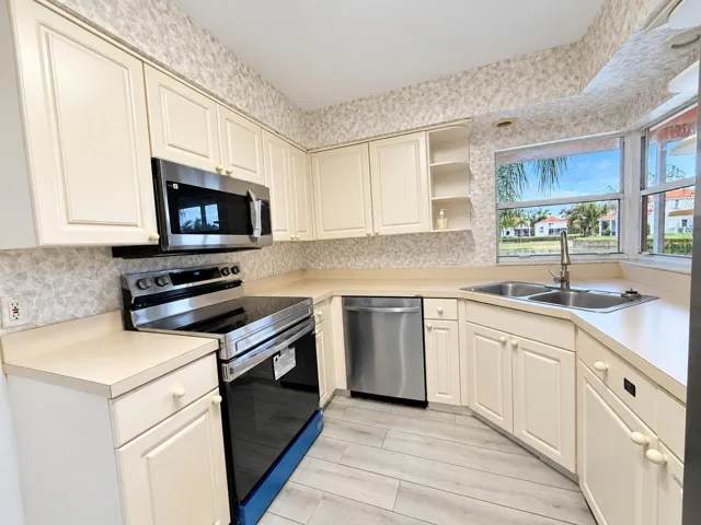 Kitchen featuring stainless steel appliances, dual basin sink, light-toned cabinetry, light-toned countertops