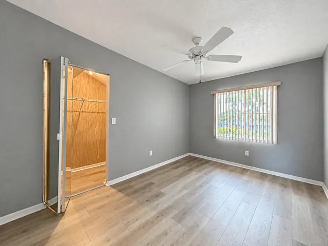 Wood-finish flooring, ceiling fan, and window with vertical blinds