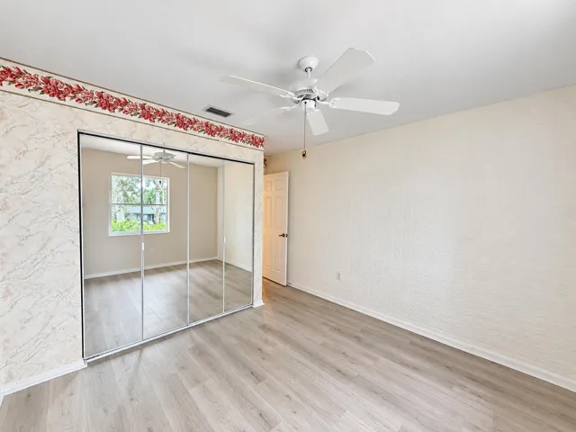 Wood-finish flooring, ceiling fan, mirrored closet doors, and textured wall finish