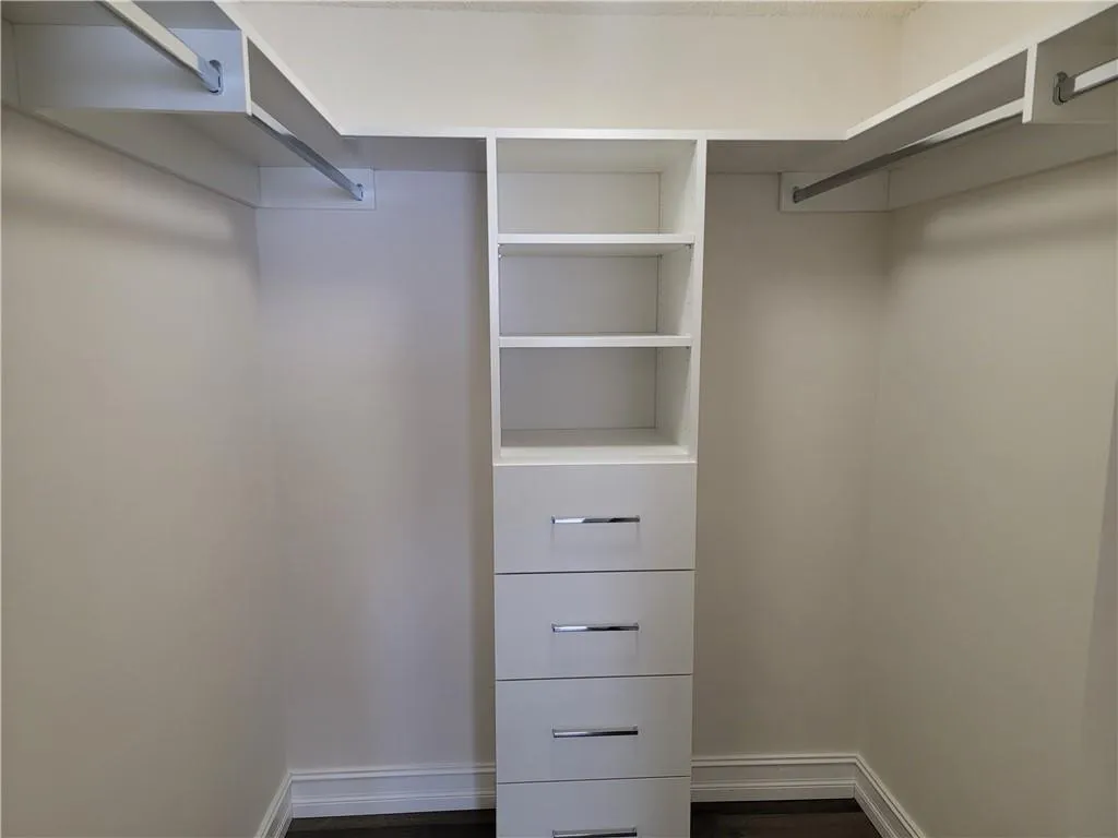Built-in closet system featuring multiple shelves, hanging rods, and four drawers with polished chrome hardware