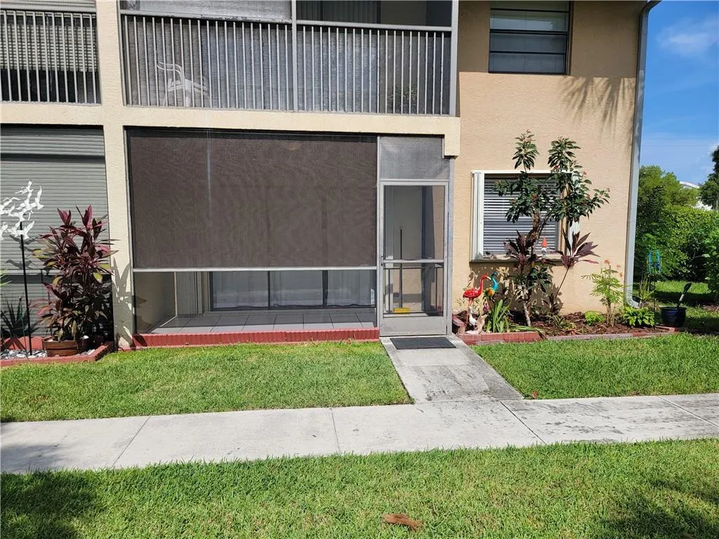 Screened patio with privacy shade, concrete walkway, and landscaped garden beds
