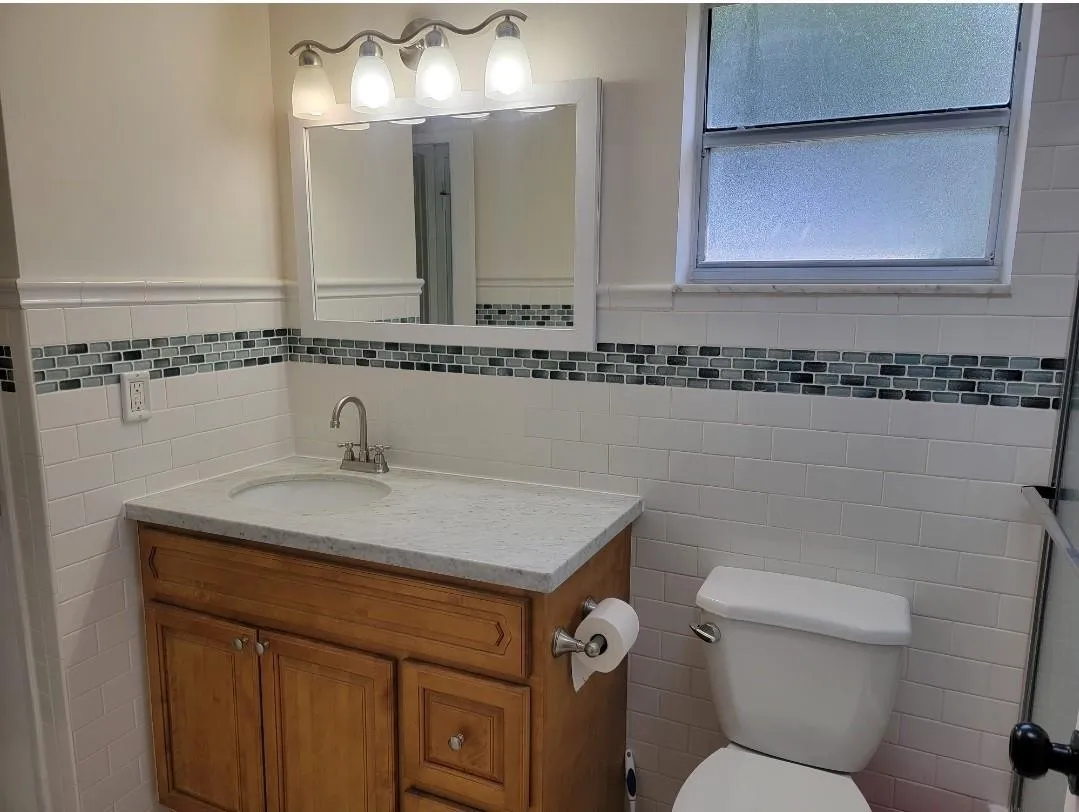 Wood-finish vanity with a light-toned countertop, undermount sink, and polished chrome faucet