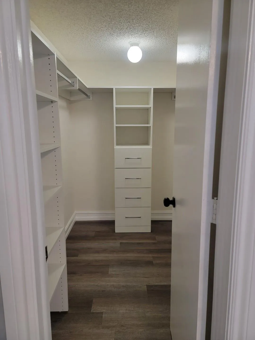 Built-in closet organization system featuring adjustable shelving, integrated drawers with horizontal pulls, and hanging rods