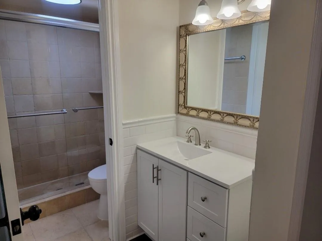 White shaker vanity with brushed nickel hardware, integrated sink, and white countertop