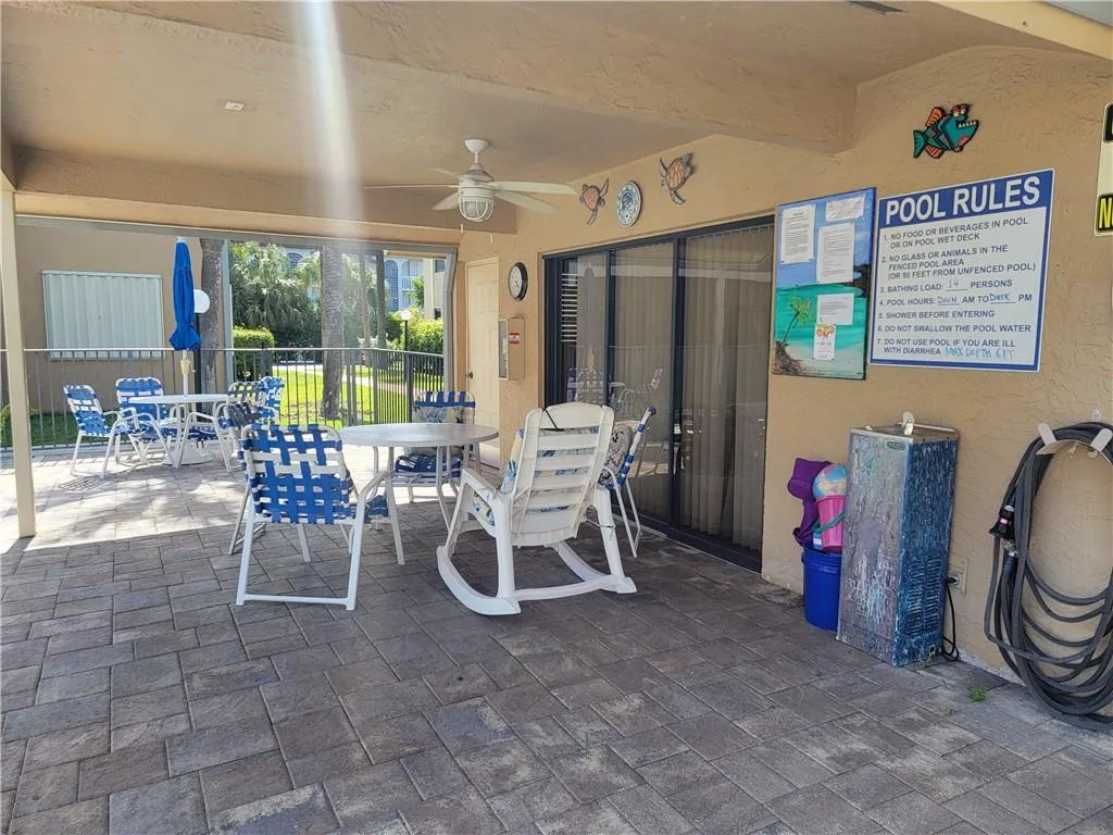 Covered patio area featuring a ceiling fan, sliding glass door, and paver flooring