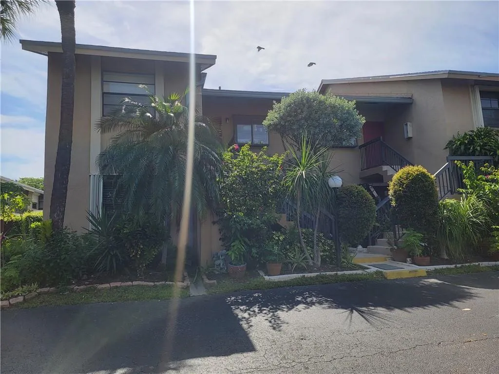 Stucco exterior with mature landscaping and multiple entry points
