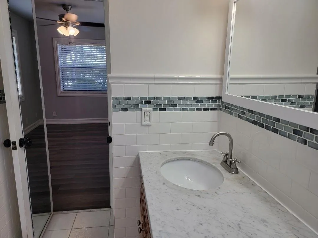 Vanity with an integrated sink, polished chrome faucet, and stone countertop