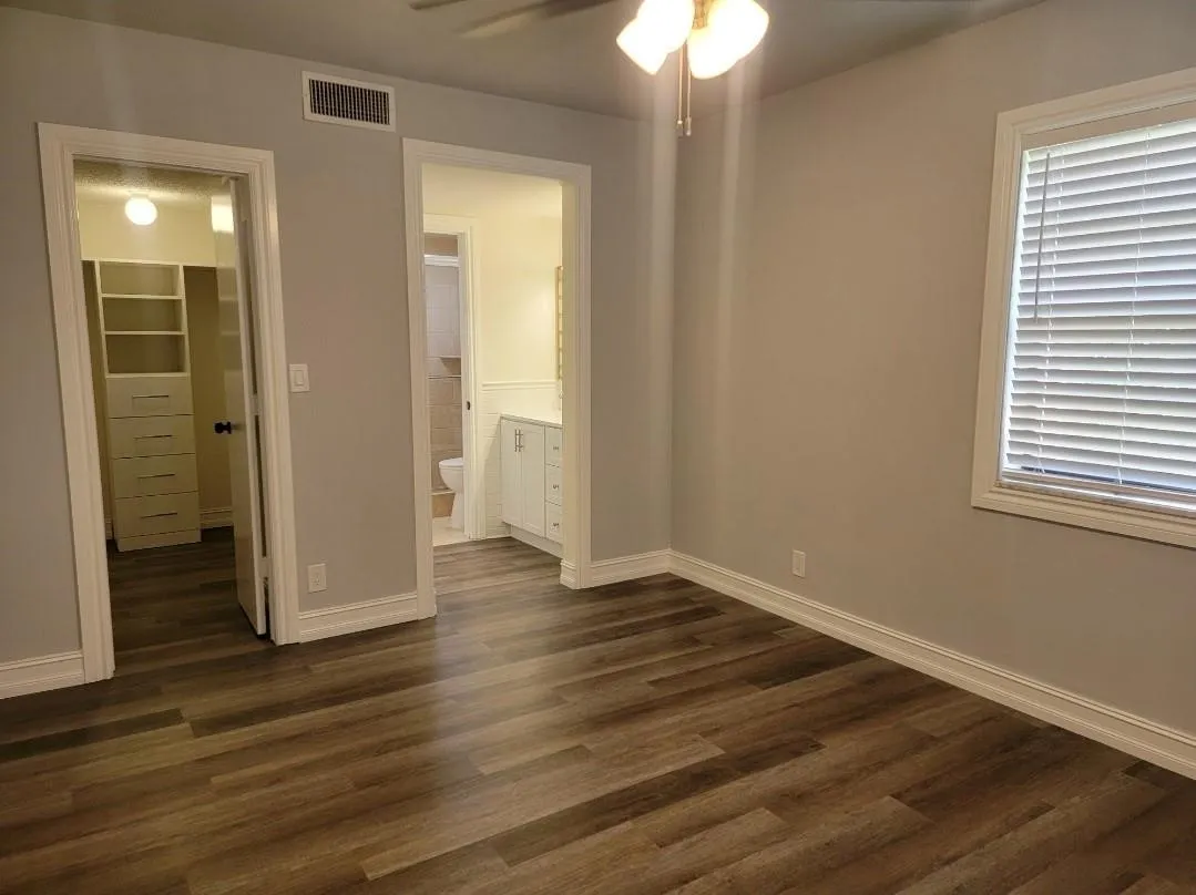 Wood-finish flooring, ceiling fan with light fixture, window with blinds, and neutral wall tones