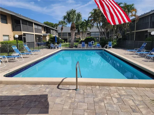Community swimming pool with paver decking and surrounding privacy fencing