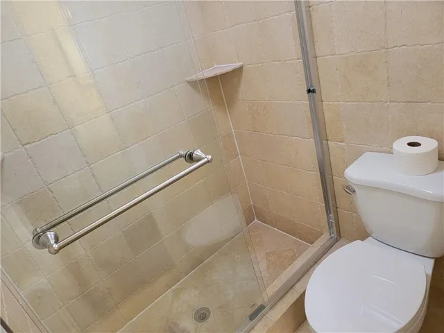 Tiled shower enclosure with a clear glass door and brushed nickel hardware