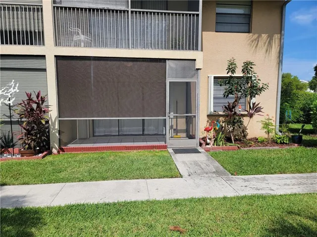 Screened patio with privacy shade, concrete walkway, and landscaped garden beds