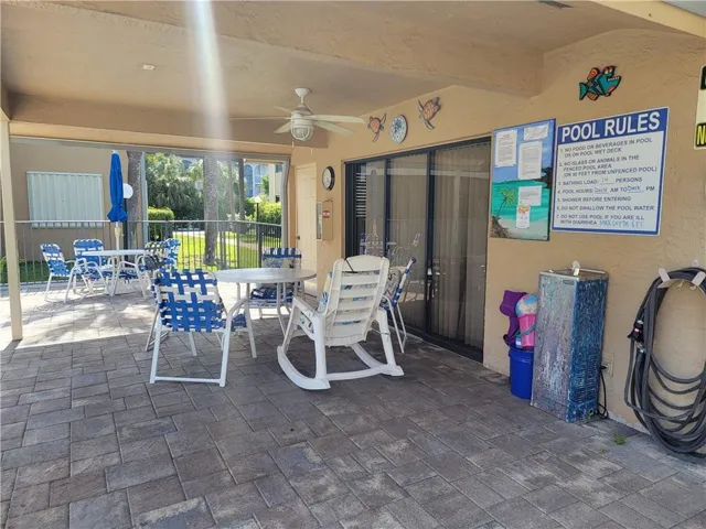 Covered patio area featuring a ceiling fan, sliding glass door, and paver flooring