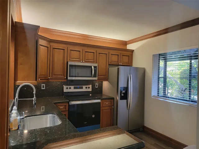 Kitchen featuring wood-finish cabinetry, dark speckled countertops, and stainless steel appliances