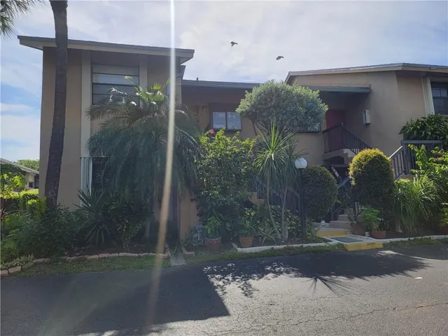 Stucco exterior with mature landscaping and multiple entry points