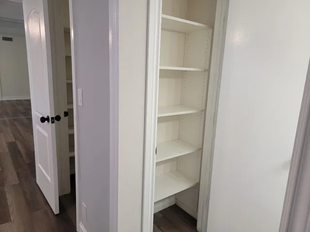 Built-in shelving with adjustable white shelves, flat-panel interior doors, and wood-finish flooring
