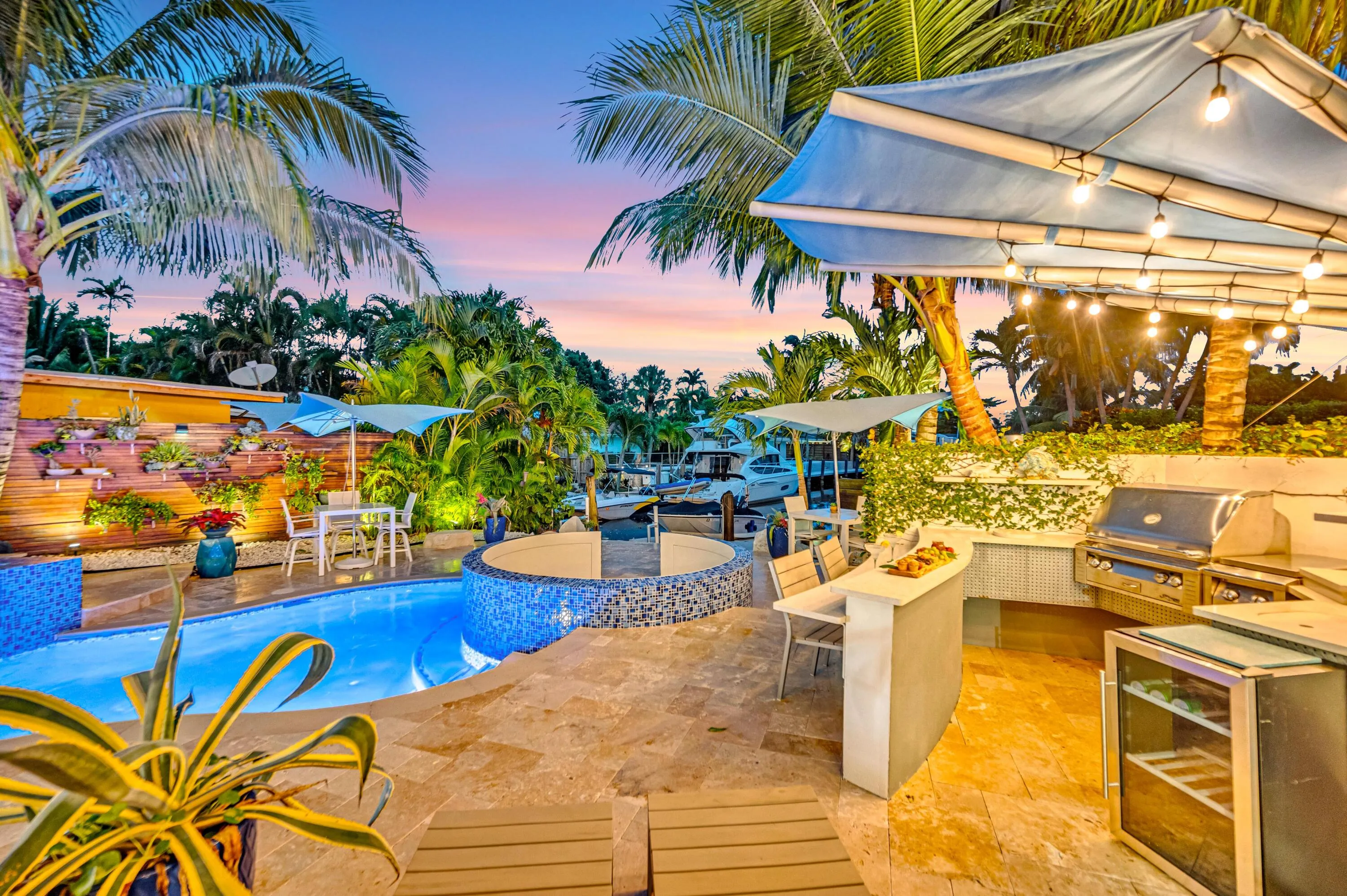 Resort-style outdoor living area with a built-in grill station, outdoor bar, and integrated pool