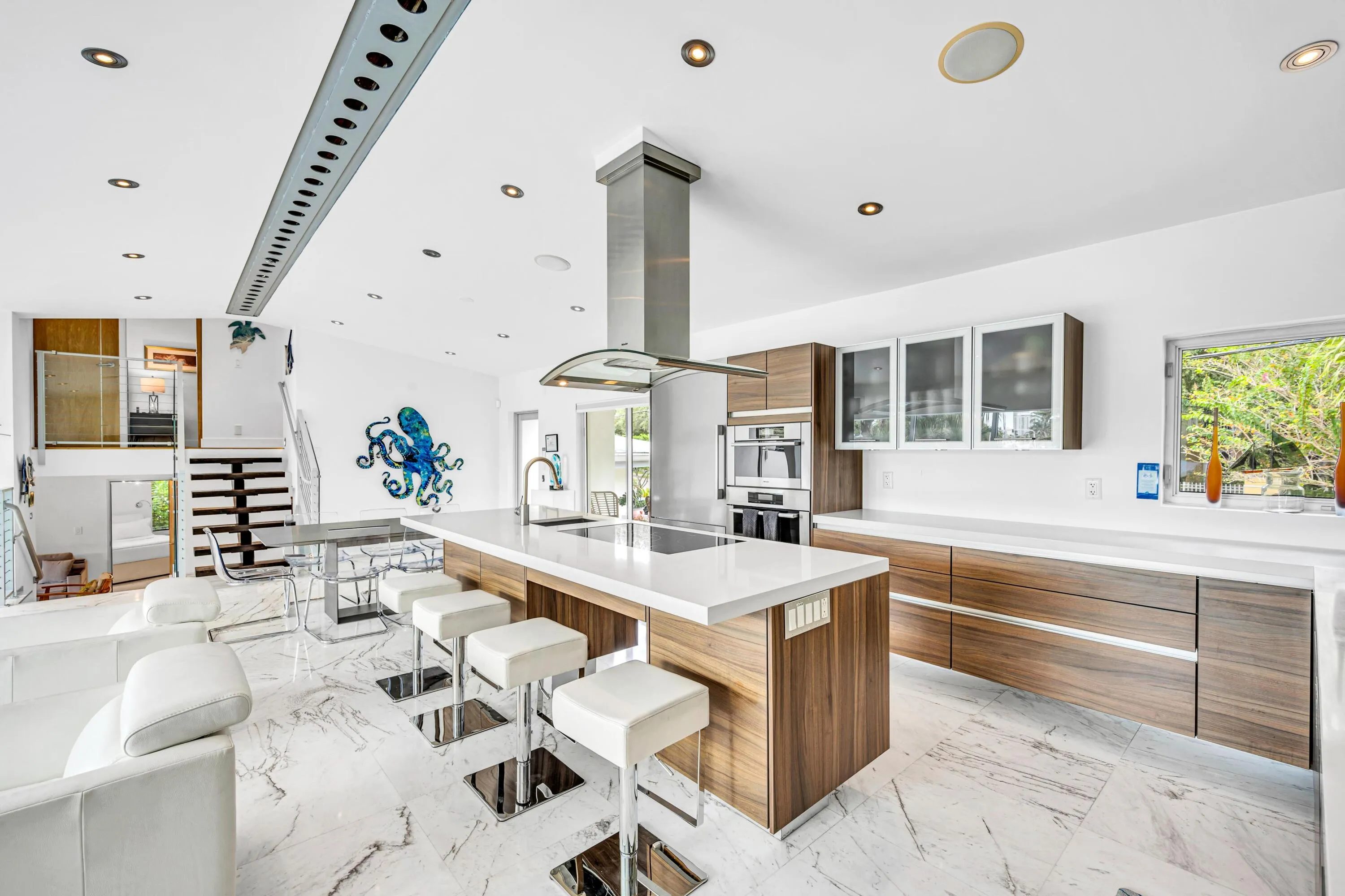 Open-concept kitchen featuring an expansive island, wood-finish cabinetry, integrated stainless steel appliances, and recessed lighting