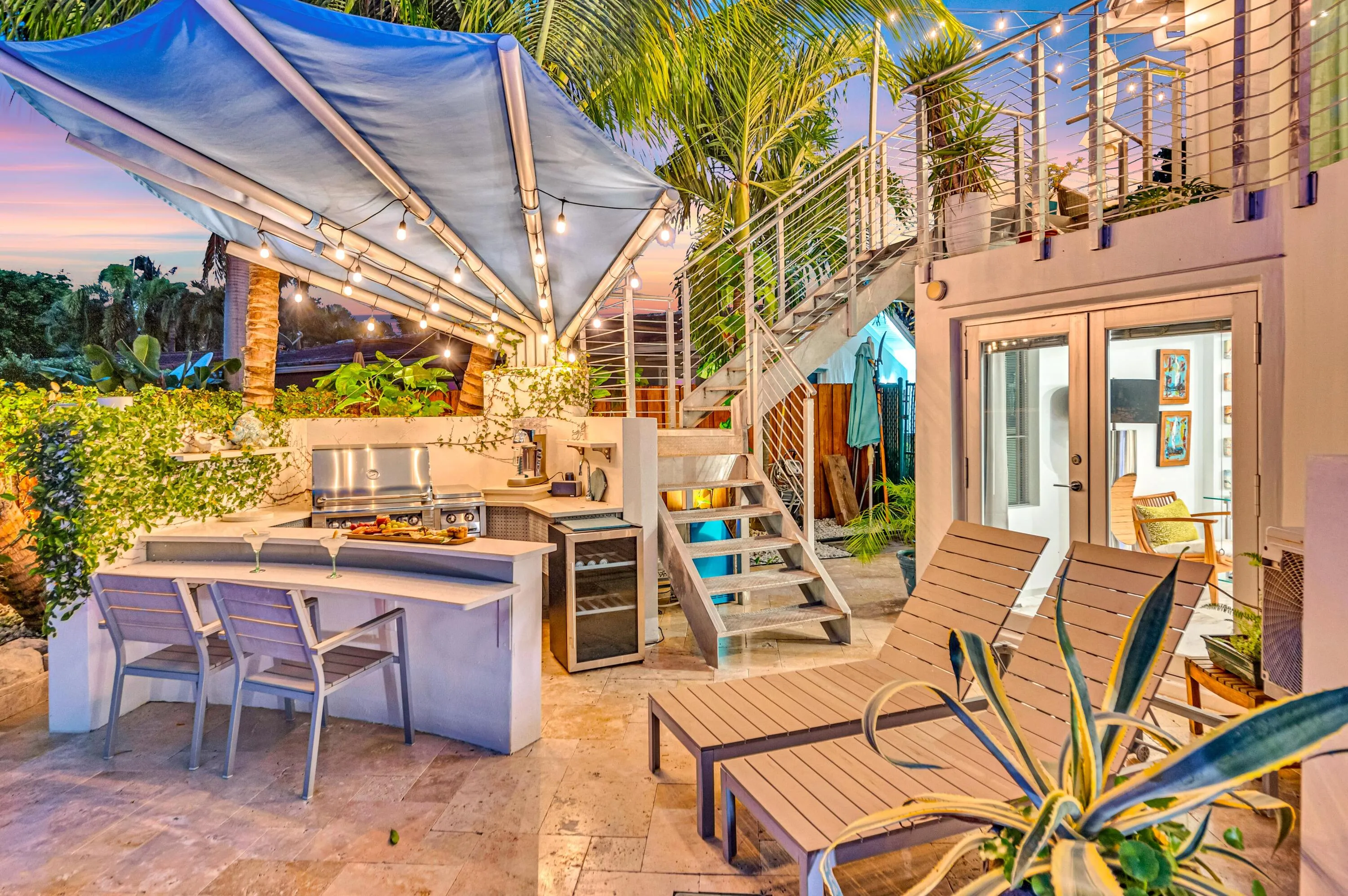 Outdoor kitchen with stainless steel grill, under-counter beverage cooler, and built-in bar seating